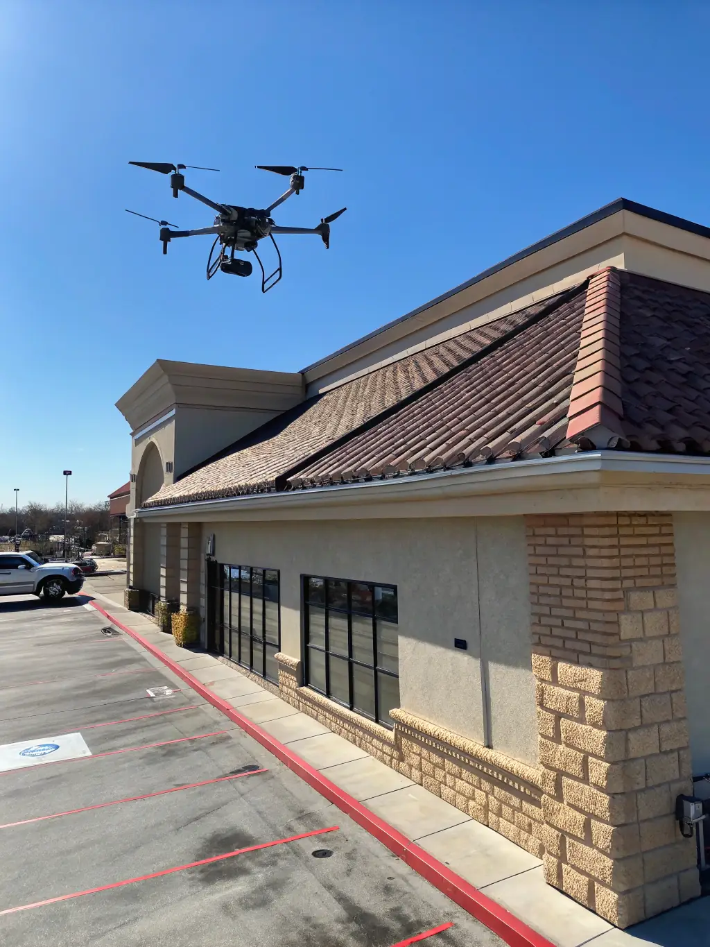 A close-up of a thermal camera mounted on a drone, capturing detailed thermal data of a building's facade, used by Amped Aerial for thermal inspections.